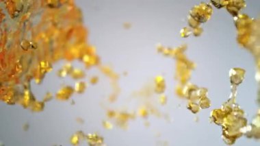 Işık Arkaplanı 'ndaki Altın Sıvı Akımı' nın Süper Yavaş Çekimi. Yüksek Hız Sinema Kamerası, 4K.