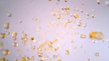 Hafif Arkaplanda Uçan Altın Sıvı Düşüşü 'nün Süper Yavaş Çekimi. Yüksek Hız Sinema Kamerası, 4K.