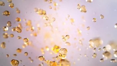 Hafif Arkaplanda Uçan Altın Sıvı Düşüşü 'nün Süper Yavaş Çekimi. Yüksek Hız Sinema Kamerası, 4K.