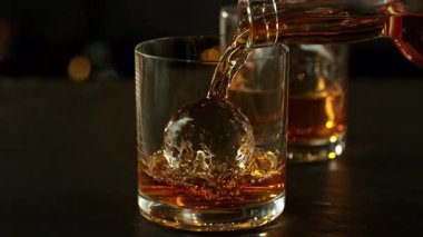 Süper Yavaş Çekim Viskiyi Barda Buzlu Küre ile Bardağa 1000 fps hızla dök. 4K 'da Yüksek Hız Sinema Kamerası ile çekildi..