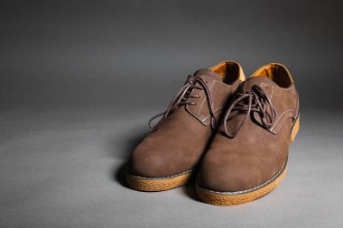 Gri arkaplanda kahverengi süet dantelli ayakkabılar..