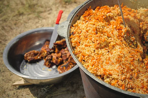 stock image Traditional oriental pilaf in big cauldron on a sunny day outdoor. Real central asian pilaf in the steppe.