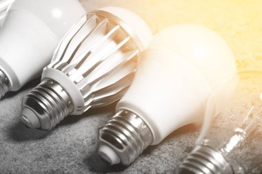 Yanan lamba ve çeşitli LED lambalar. Gri arka planda E-27 tabanlı ve ışıklı..