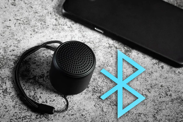 Siyah mini bluetooth hoparlörü ve bluetooth 'lu akıllı telefon.