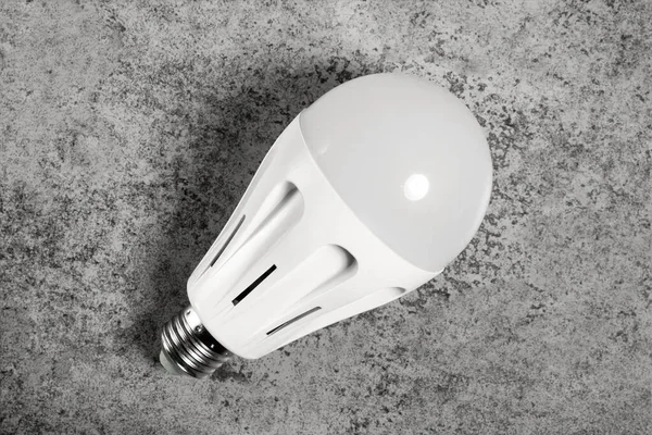 LED energy-saving lamp with E27 screw cap base on gray background.