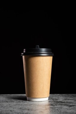 Brown Paper cup of coffee or tea on a black background with copy space, vertical mock up.