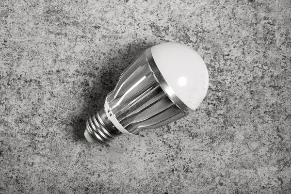 LED energy-saving lamp with aluminum radiator and E27 screw cap base on gray background.