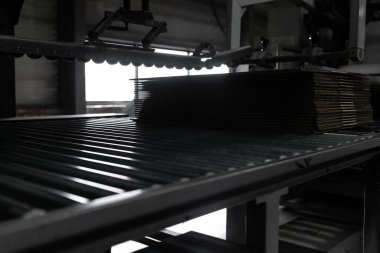 Close-up on the conveyor for the creation of boxes for packaging from recycled paper.
