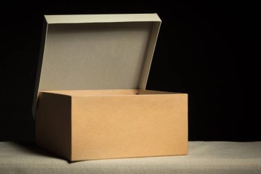 Open cardboard box on black background, copy space.