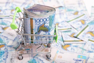10000 Kazakhstan tenge in a shopping cart against the background of Kazakh money.