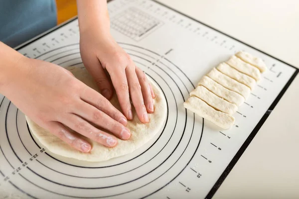Close-up of hands kneading rolled out dough on a kitchen baking mat with round markings of different diameters.
