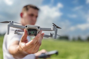 Odaklanamayan bir uzaktan kumandalı bir kuadkopter operatörü açık havada bir dron tutuyor..