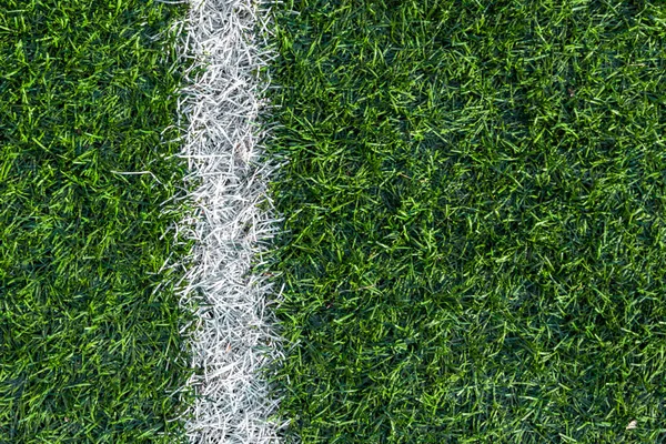 Futbol sahasının yeşil çimlerinde beyaz çizgili izler var..