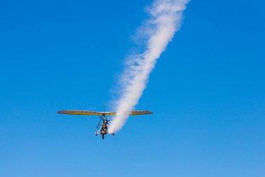 Tekerlekli beşiği olan bir paraglider mavi gökyüzünde beyaz bir iz bırakır..