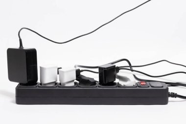 Beyaz arka planda birçok eklentisi olan siyah uzatma kablosu.