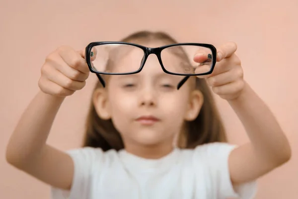集中力のない就学前の女の子のクローズアップポートレート彼女の前でディオプターの眼鏡を持っています — ストック写真