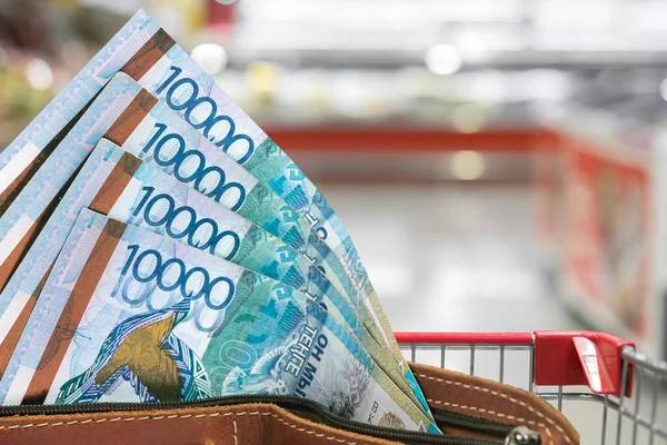 Kazakistan 'da gıda ürünlerinin fiyatları yükseliyor. Bulanık bir marketin arka planında cüzdanda bir tenge.
