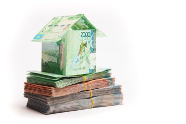 Kazak parasından yapılmış bir ev. Tenge paketlerinin üzerinde duruyor. İpotek konsepti, gayrimenkul değerlendirmesi, kopya alanı.