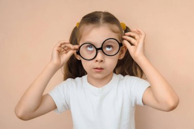 İlkokul çağındaki kafası karışmış küçük kız ilk kez gözlük taktı..