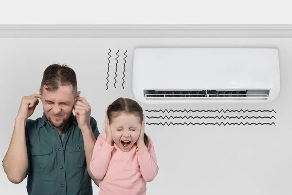 The air conditioner makes loud sounds, noises and vibrations. Father with child close their ears.