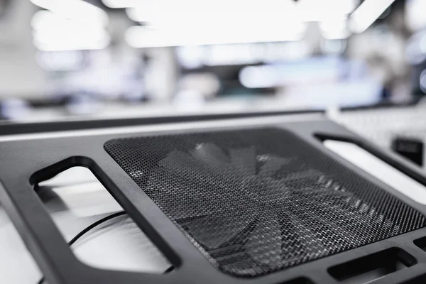 A cooling pad or stand with a fan for a laptop stands on a shelf in a store.