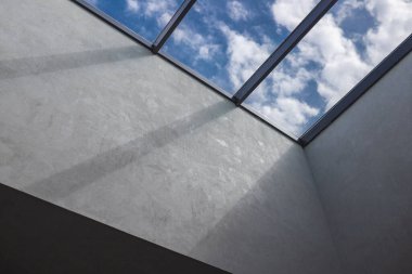 İçerideki ikinci ışık, tavanda bir pencere arkasında bulutlu bir gökyüzü..