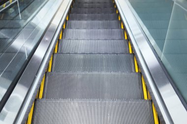 Yürüyen merdivenlerin üst görüntüsü modern binalar veya metro istasyonları.