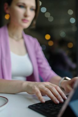 Bir kafede dizüstü bilgisayarda çalışan genç bir iş kadını, serbest çalışma konsepti, ellerine odaklan, dikey.