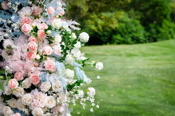 Spray roses of different colors on the left side of the photo in front of a green lawn field. High quality photo