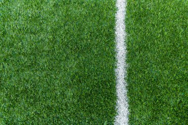 Futbol sahasının yeşil çimlerinde dikey beyaz çizgiler var..