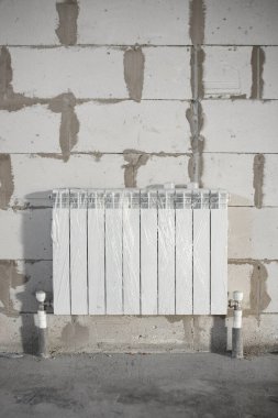 İnşaat sırasında kaba bitişe alüminyum ısıtma kaloriferleri yerleştirildi, zemindeki borular monte edildi, kopyalama alanı, dikey.