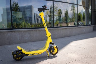 Şehir ortamında üzerinde Yandex Go logosu olan sarı renkli bir scooter. Almaty, Kazakistan - Haziran 05, 2023
