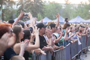 Çitin arkasında çağdaş etnik müzik festivalinde sahne almayı bekleyen bir hayran topluluğu. Almaty, Kazakistan - 11 Haziran 2023