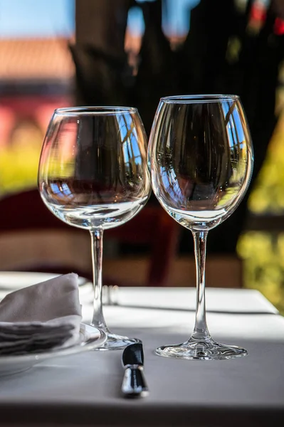 2 wine glasses for different types of wine stand on a served dining table in a luxury restaurant.