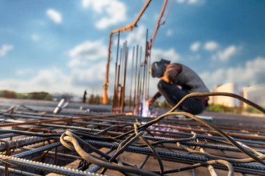 Kaynakçı elektrikli kaynak bir inşaat alanında güçlendirilmiş beton yapılar için yapılmış çelik bir çerçeve, seçici yumuşak odaklı..