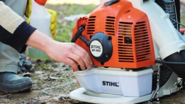 Bir adam sırt çantalı bir motor püskürtücüsü STIHL SR450 'nin motoruna yakıt ikmali için motor kapağını açıyor. Almaty, Kazakistan - 23 Mart 2023
