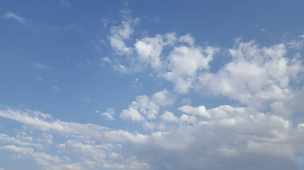 A picturesque natural landscape featuring a vibrant electric blue sky with fluffy white cumulus clouds, stretching towards the horizon over a vast grassland prairie