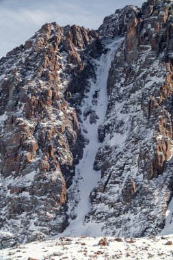 Orta Asya 'daki Tien Shan dağlarında, Almaty yakınlarındaki Kazakistan' da bulunan kar tepeli kayaların resimsel dikey arka planı..