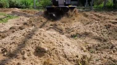 Çalışkan bir çiftçi, ekin ekimi için toprağı etkin bir şekilde hazırlamak için tarla malzemesi kullanıyor.