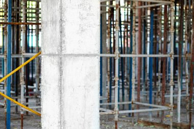 İnşaat alanında beton döşeme iskelesinin arka planına karşı güçlendirilmiş beton yapısal sütun.