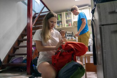 İki hevesli gezgin, sıcak bir iç mekan ortamında heyecan verici bir açık hava yolculuğu için ekipmanlarını düzenliyor.