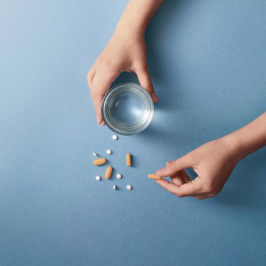 El Tutma Hapları ve Mavi Arkaplanda Bir bardak Su.