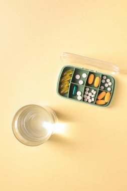 Çeşitli haplar, vitaminler ve bir bardak su, fotokopi alanı, dikey.