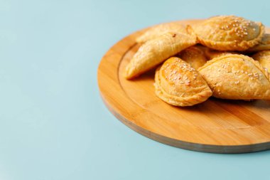 Tahta tabakta susam tohumları serpiştirilmiş tavuklu taze pişmiş Samsa turtaları, Orta Asya mutfağı..