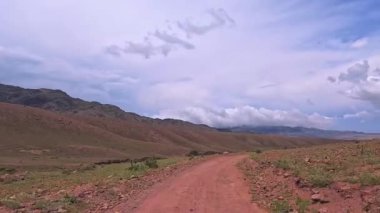 Bartogai Gölü 'ndeki dolambaçlı toprak bir yolun sakin bir görüntüsünü yaşayın. Geniş bir gökyüzü altında hareketli, renkli bir manzara, Kazakistan doğası, Almaty. 