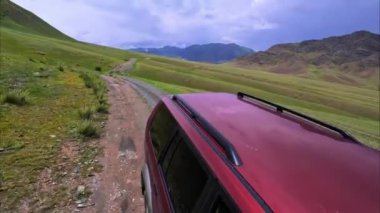 Tian Shan dağları, Orta Asya seyahati ve Kazakistan doğası ile çevrili kırsal bir yol boyunca giden kırmızı 4x4 SUV 'luk manzaralı bir araba.