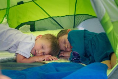 İki genç çocuğun canlı ve renkli bir kamp çadırında huzur içinde uyuduğu sevimli ve iç açıcı bir sahne.