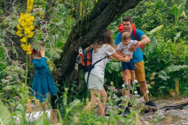 Bir aile yemyeşil bir ormanda neşeyle gezinir, doğada birlikte harika anlar paylaşır.