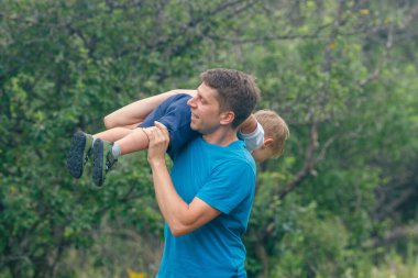 Neşeli bir baba çocuğuyla açık havada keyifli bir an geçirir. Yeşilci bir doğal ortamda, hatıralar yaratarak.