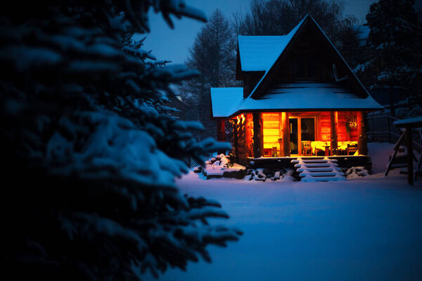 Утепленный дом в зимнем горном лесу, светлые ночные окна